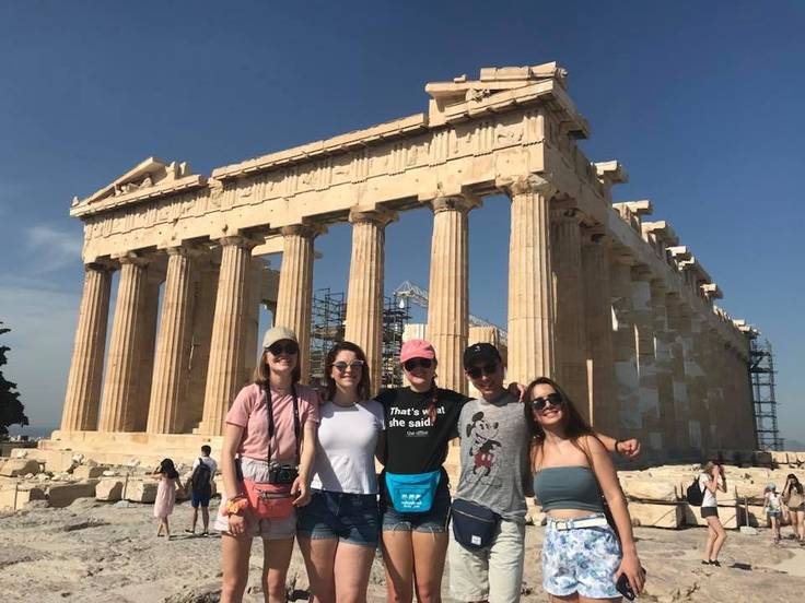 Students posing in front of ancient ruins in Greece.