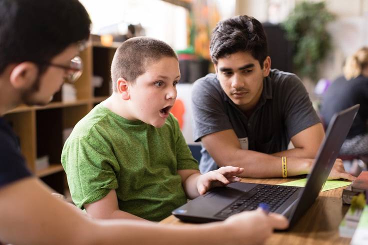 A student gets excited when he learns from Rollins students how to code a video game.
