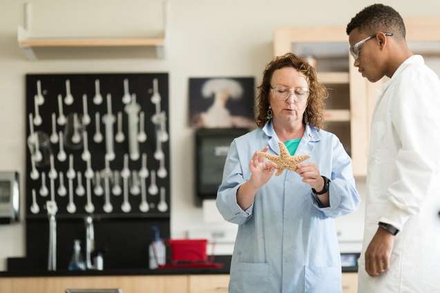 A college professor sharing her research in the lab with a marine biology student.