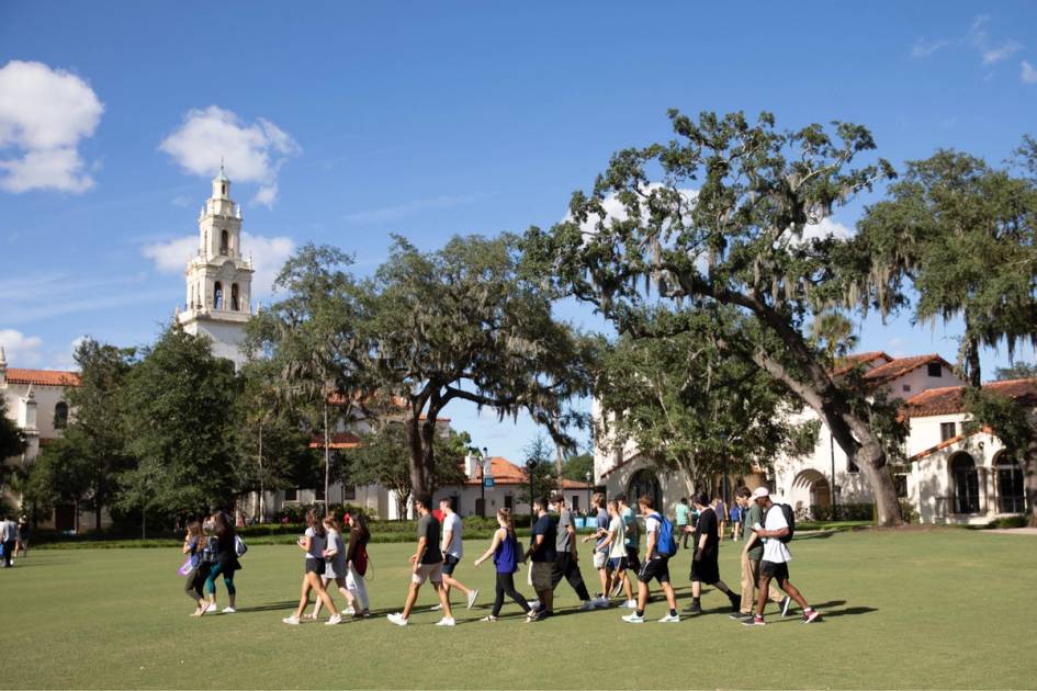 A group of students walks across Mills Lawn at Rollins College.