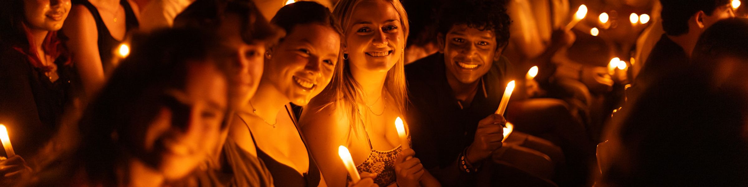 Students holding candles looking at the camera smiling