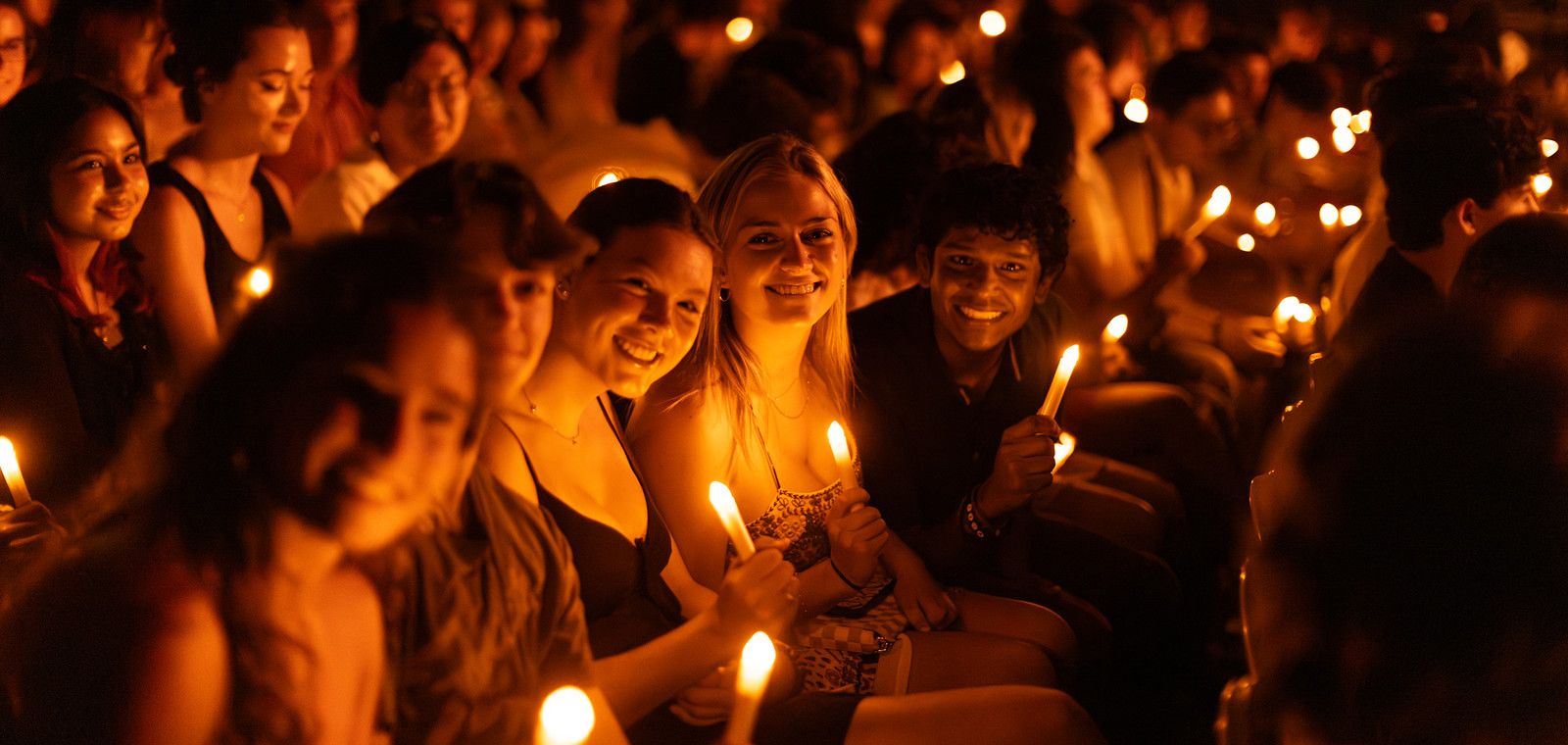 Students holding candles looking at the camera smiling