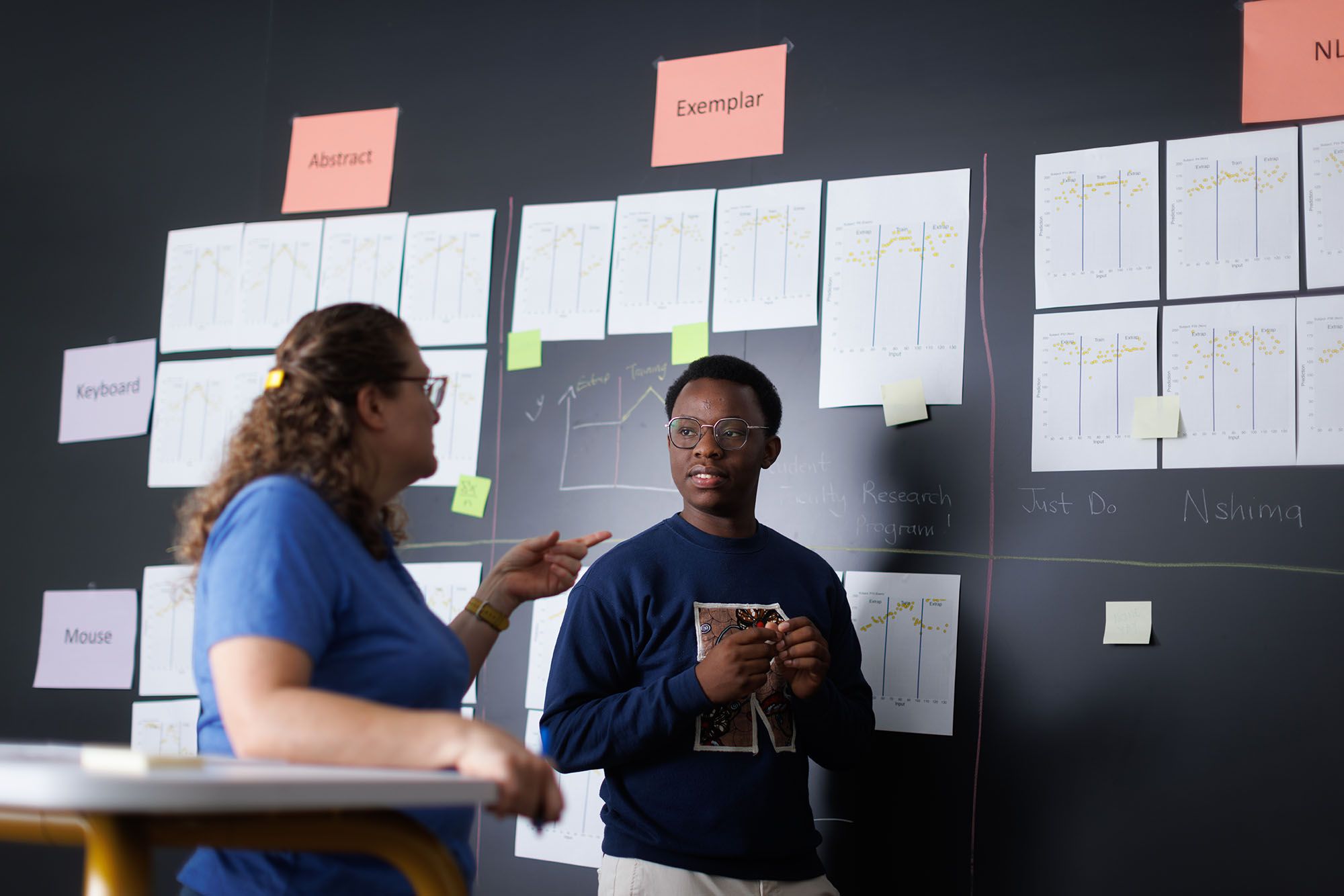 A computer science and psychology student works with a faculty member on a research project in a classroom.