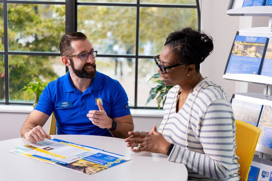 A counselor walks a prospective student through a packet of materials.