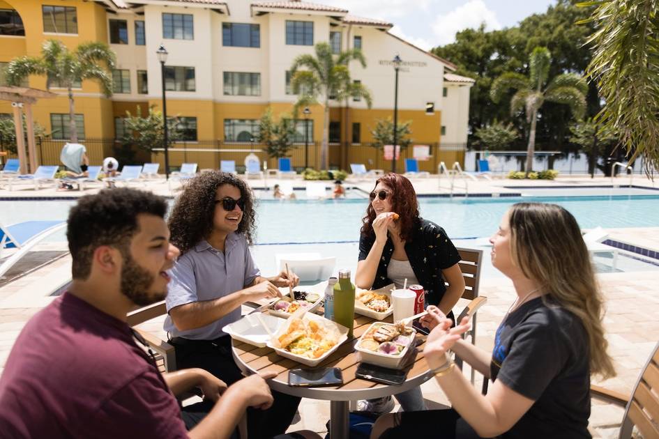 A group of Rollins students eating poolside.