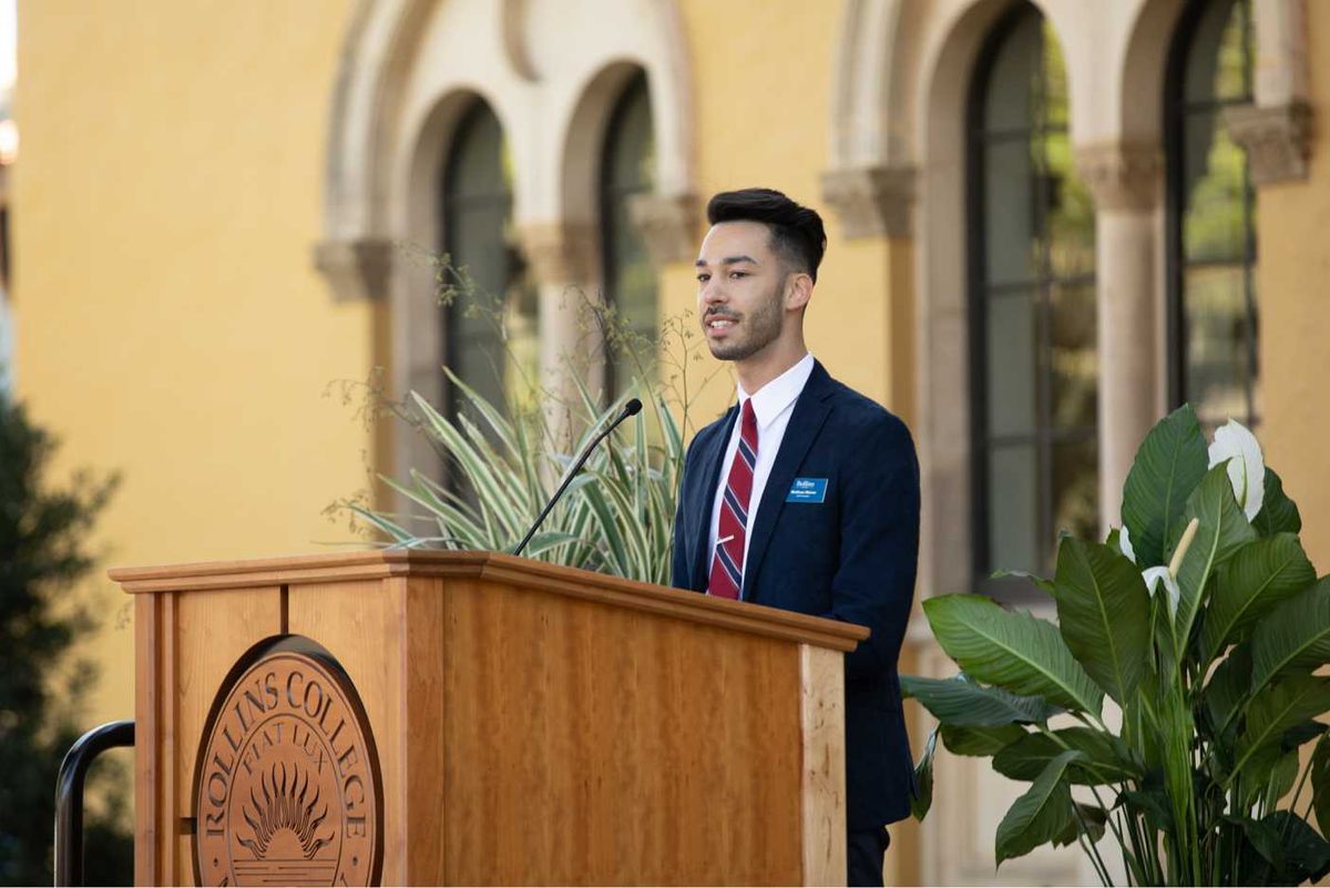 male SGA president speaks at a Rollins podium