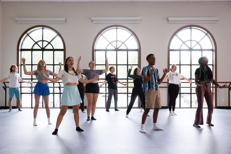 A group of students singing in a bright dance studio