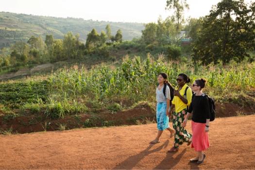 Three Rollins students walk down a clay road in Rwanda. 