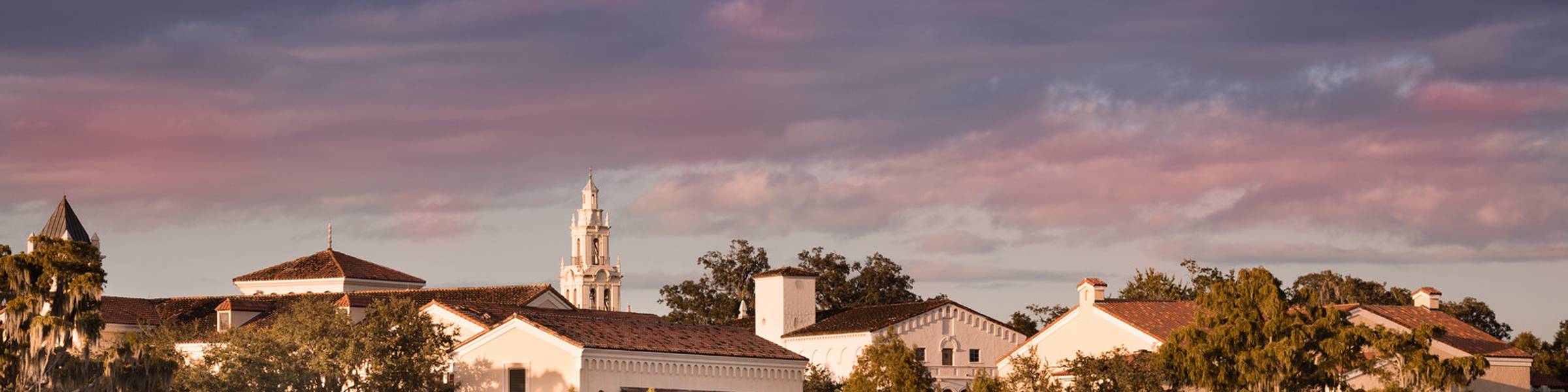 Rollins Campus sitting along Lake Virginia with a cloudy sky of pinks and purples.