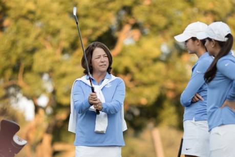 A golf coaches instructs a pair of student-athletes.