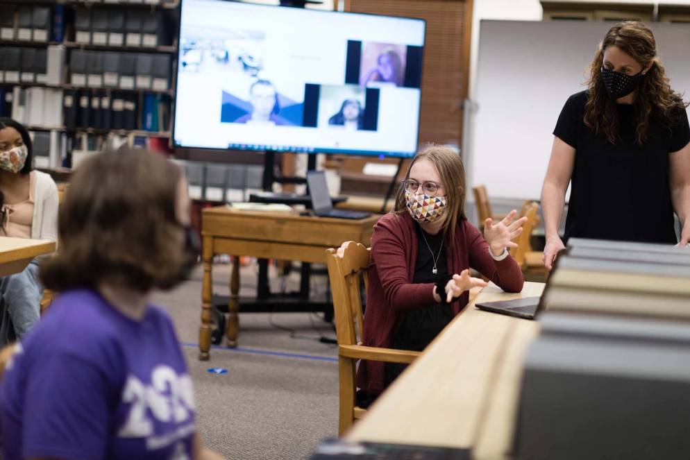 Students conduct research while a screen shows virtual participants