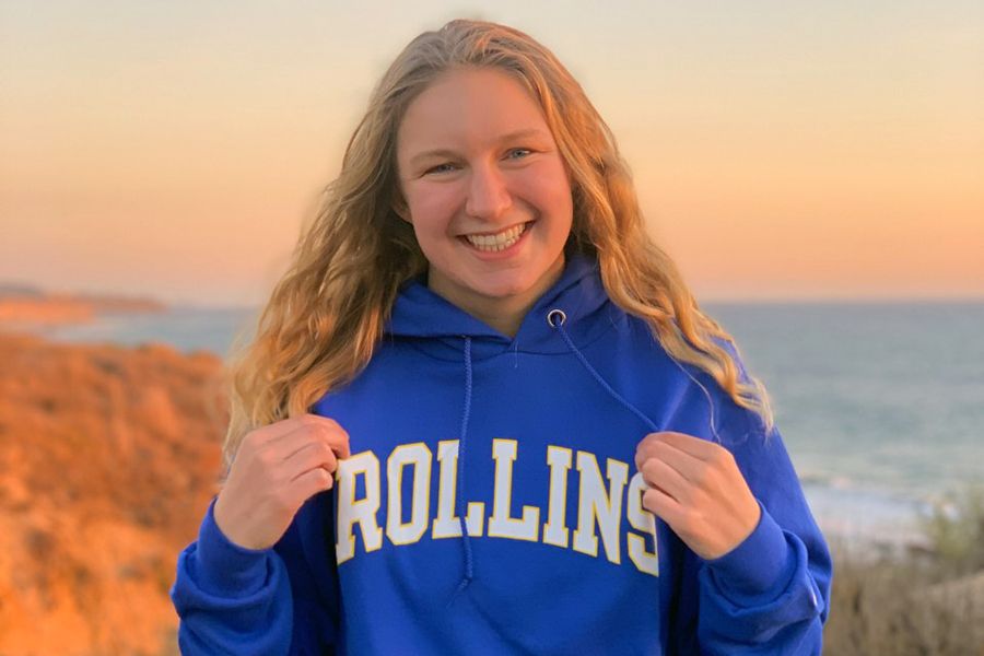 A high school student poses for a picture in a Rollins College hoodie.