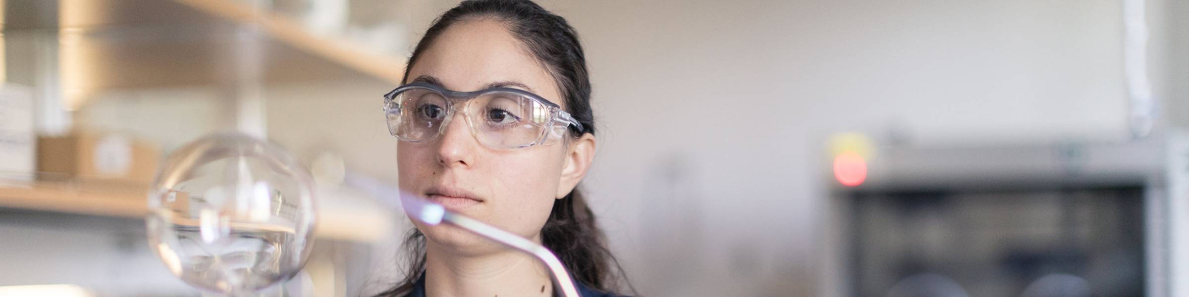 A chemist heats up a piece of lab equipment with a torch.