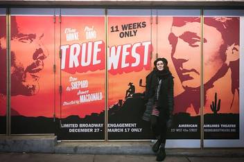 Kathleen Capdesuner in front of a poster for a Broadway play.