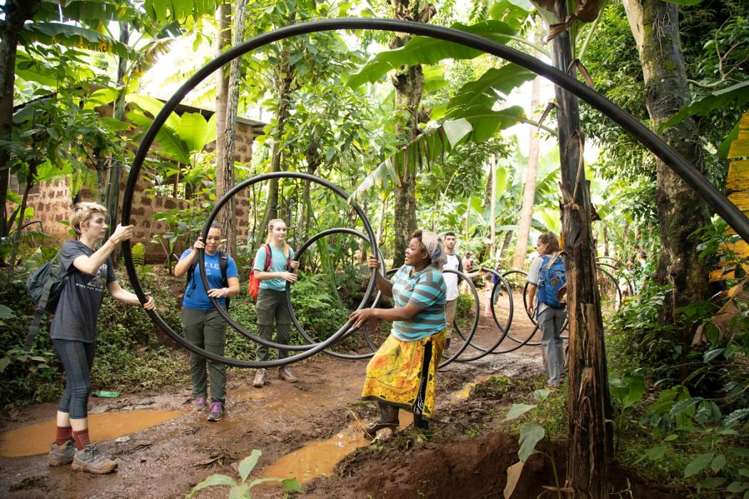 Rollins College students help carry water tubing while on an academic trip in Tanzania.