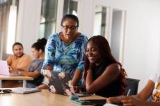 A professor works one on one with a student in a college computer science class.
