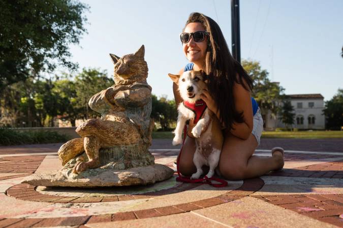 Rollins student posing with the Fox State and her puppy on Tars Plaza.