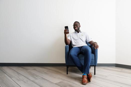 Man sitting on a chair looking at his phone smiling