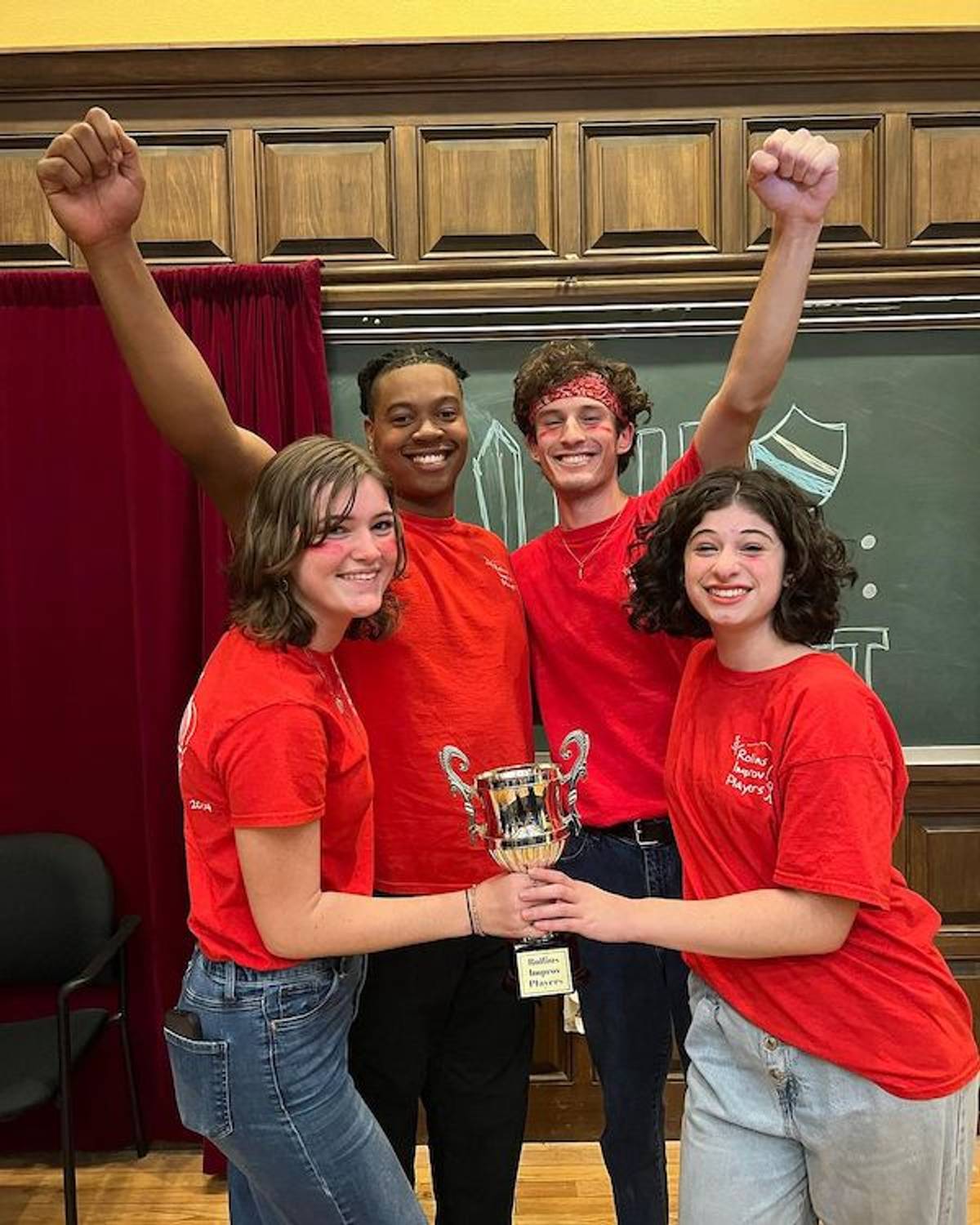 Four improvisers holding a trophy and smiling