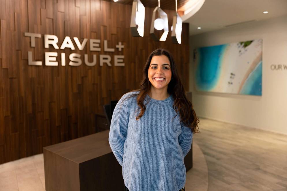 Beatriz Olivieri poses in front of the Travel + Leisure sign at the company's Orlando headquarters.