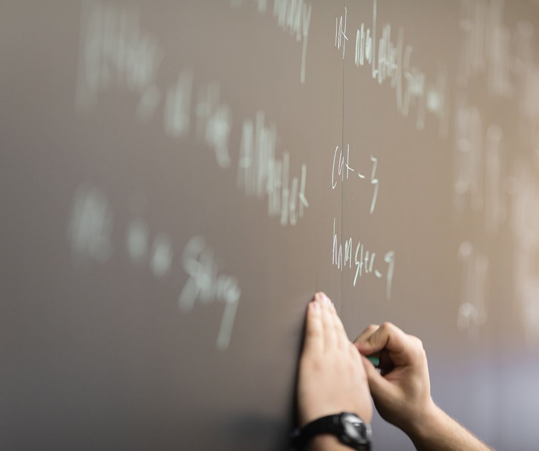 A computer science student writes codes on a blackboard.