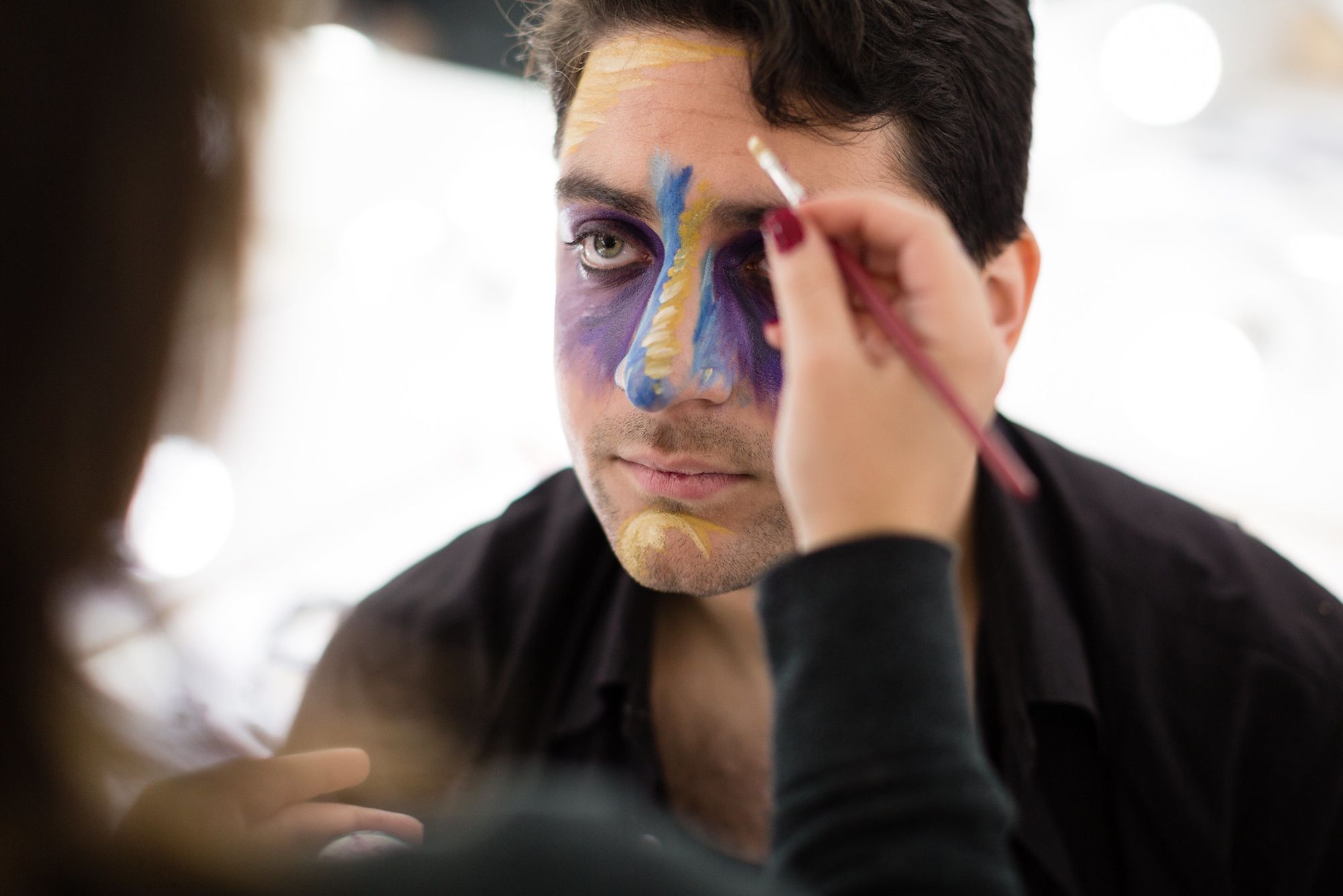 Theatre student undergoing professional makeup application for a performance.