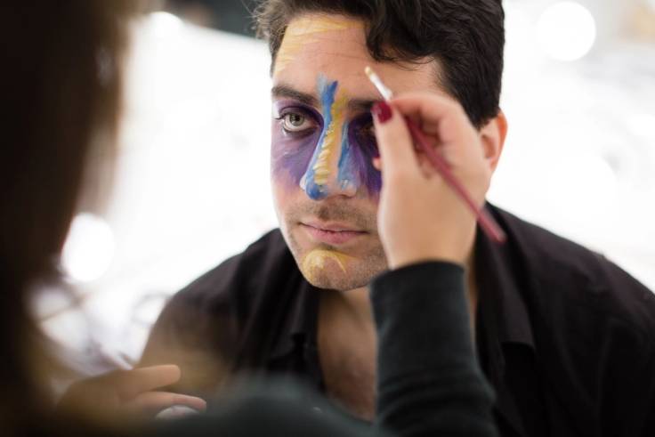 A Rollins student applies stage makeup to another student's face.