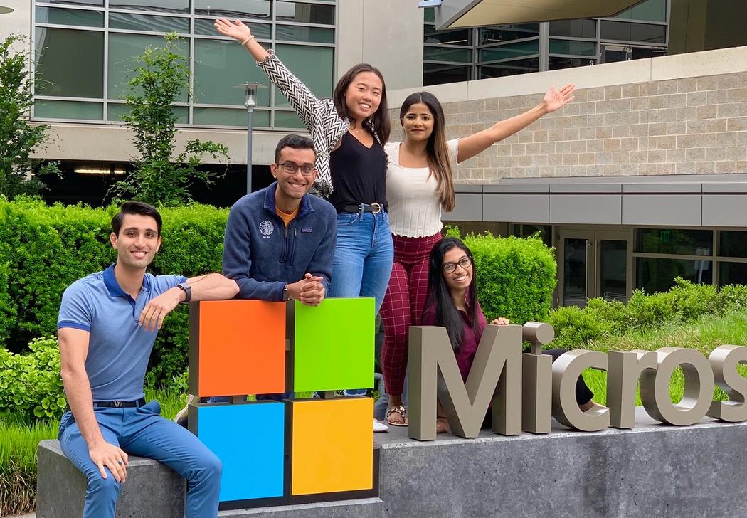 student interns stand on a Microsoft sign