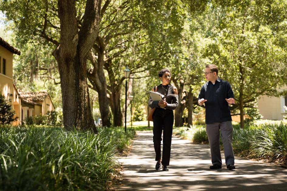 A Rollins student walks on campus with a professor.