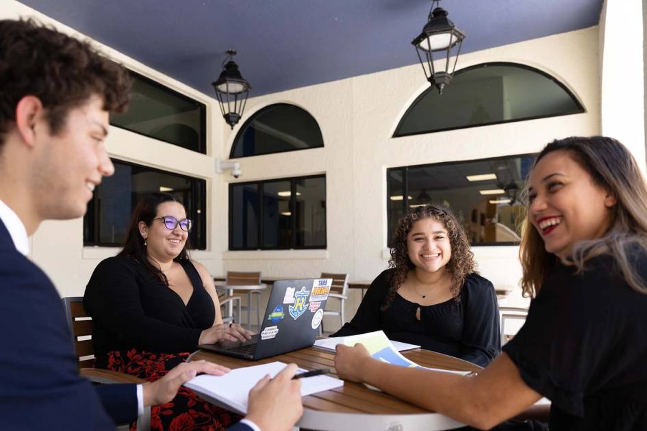 A group of students meets around a table on the Lakeside Neighbordhood pool deck.