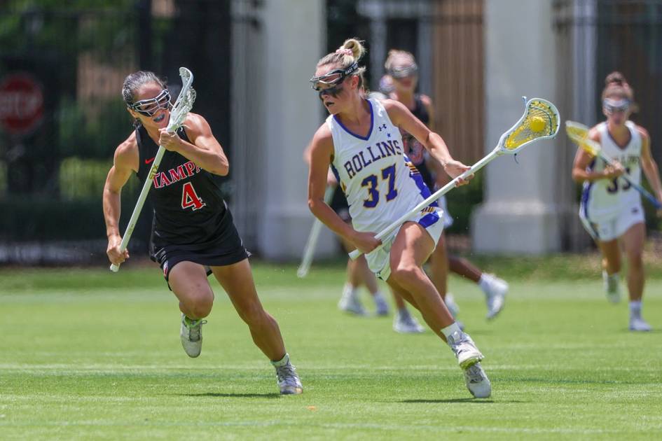 A women's lacrosse player runs past an opponent.