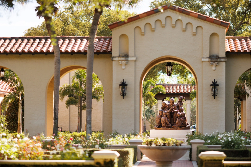 Bronze Fred Rogers ’51 ’74H sculpture framed by Mediterranean arches in a lush garden