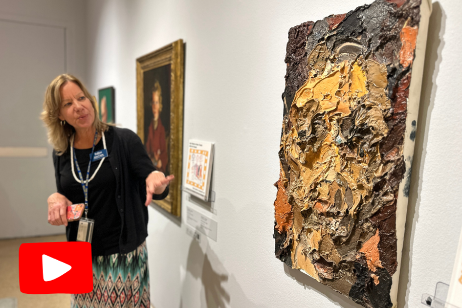 Woman in art gallery gestures to painting of a distorted face
