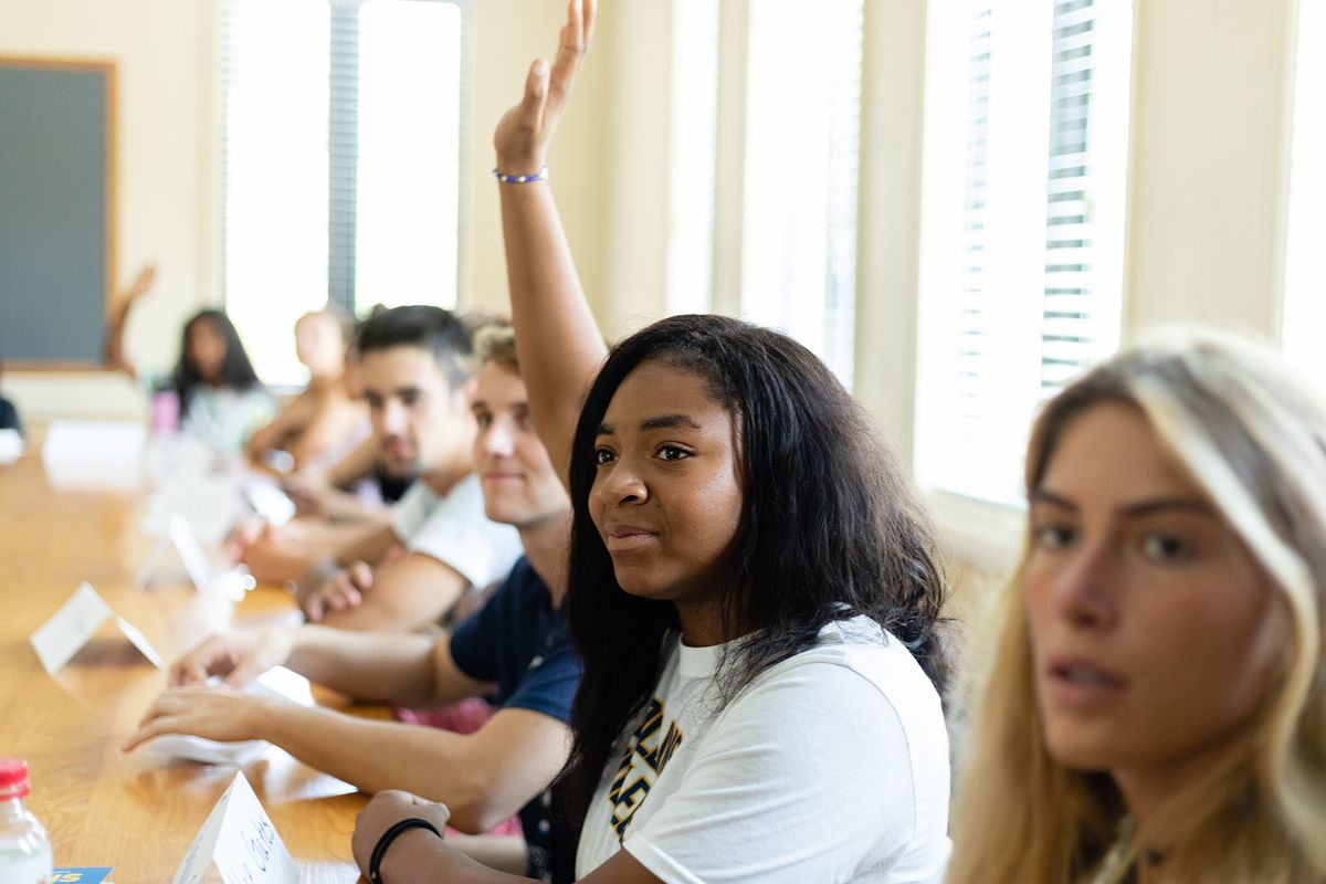 A student raises her hand to be called on during a college class.