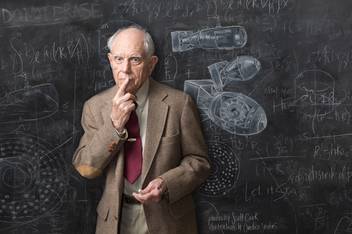 John Bistline ’44 pictured in front of a chalkboard bearing a loose sketch of the nuclear bomb.