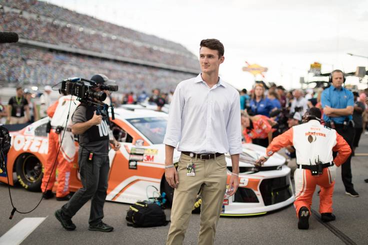 A student intern poses in front of a race car at Daytona Speedway.