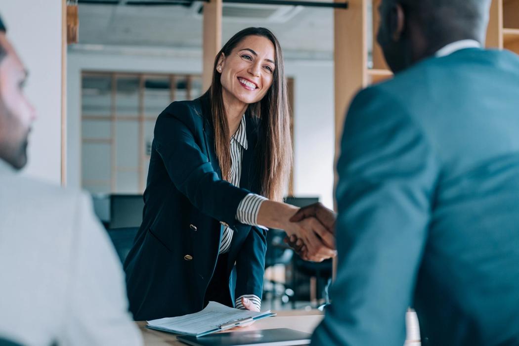 A human resources professional shakes the hand of a new employee.