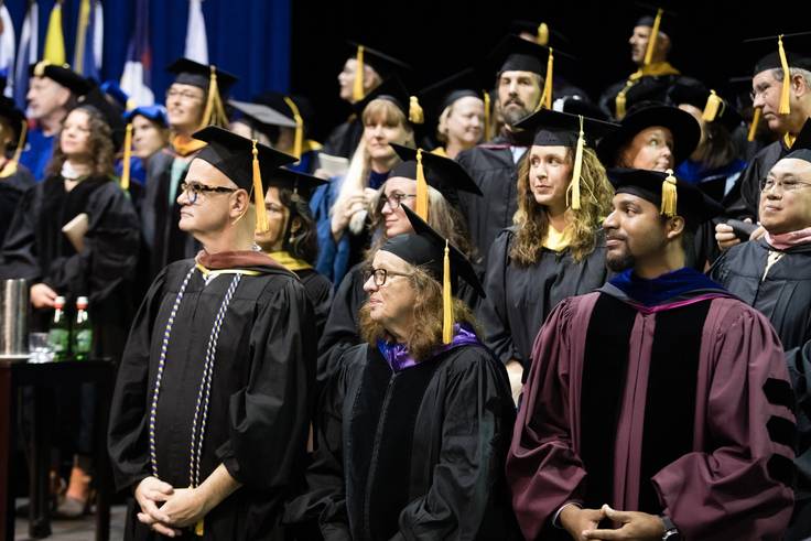 Professors watch students graduate.