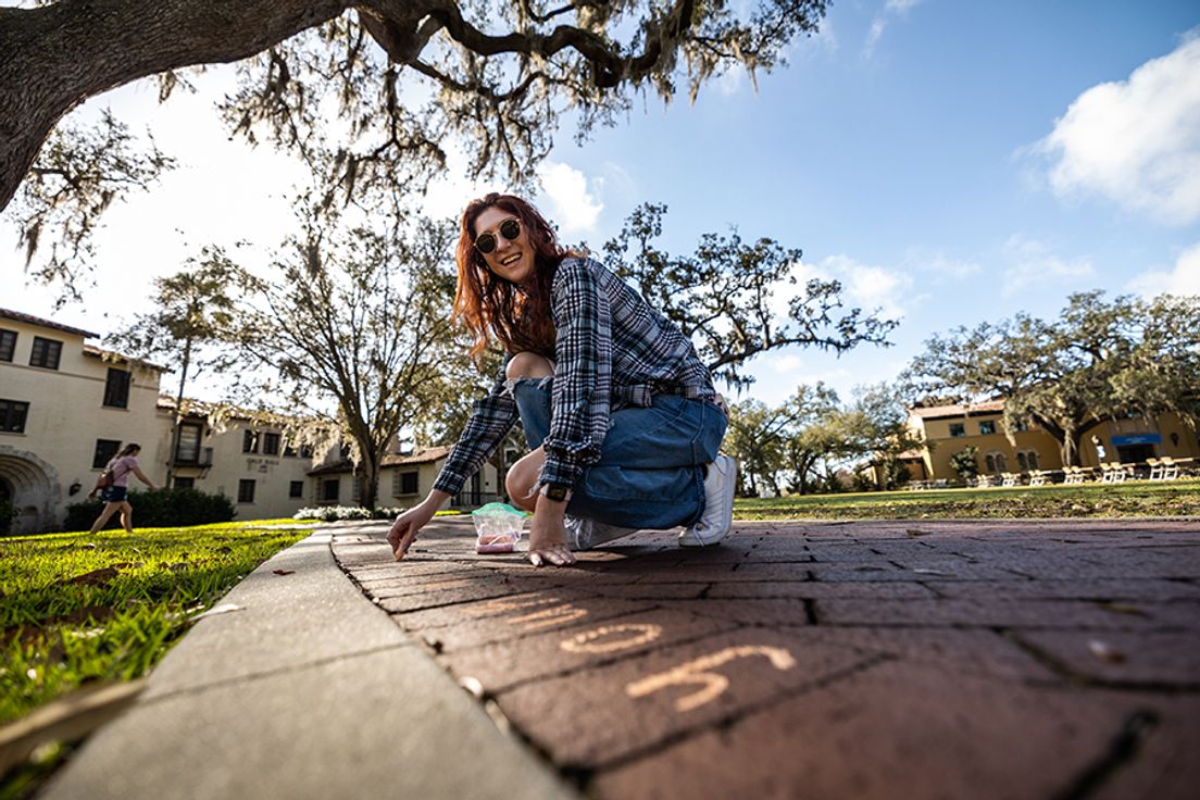 Rollins student writing kind messages in chalk