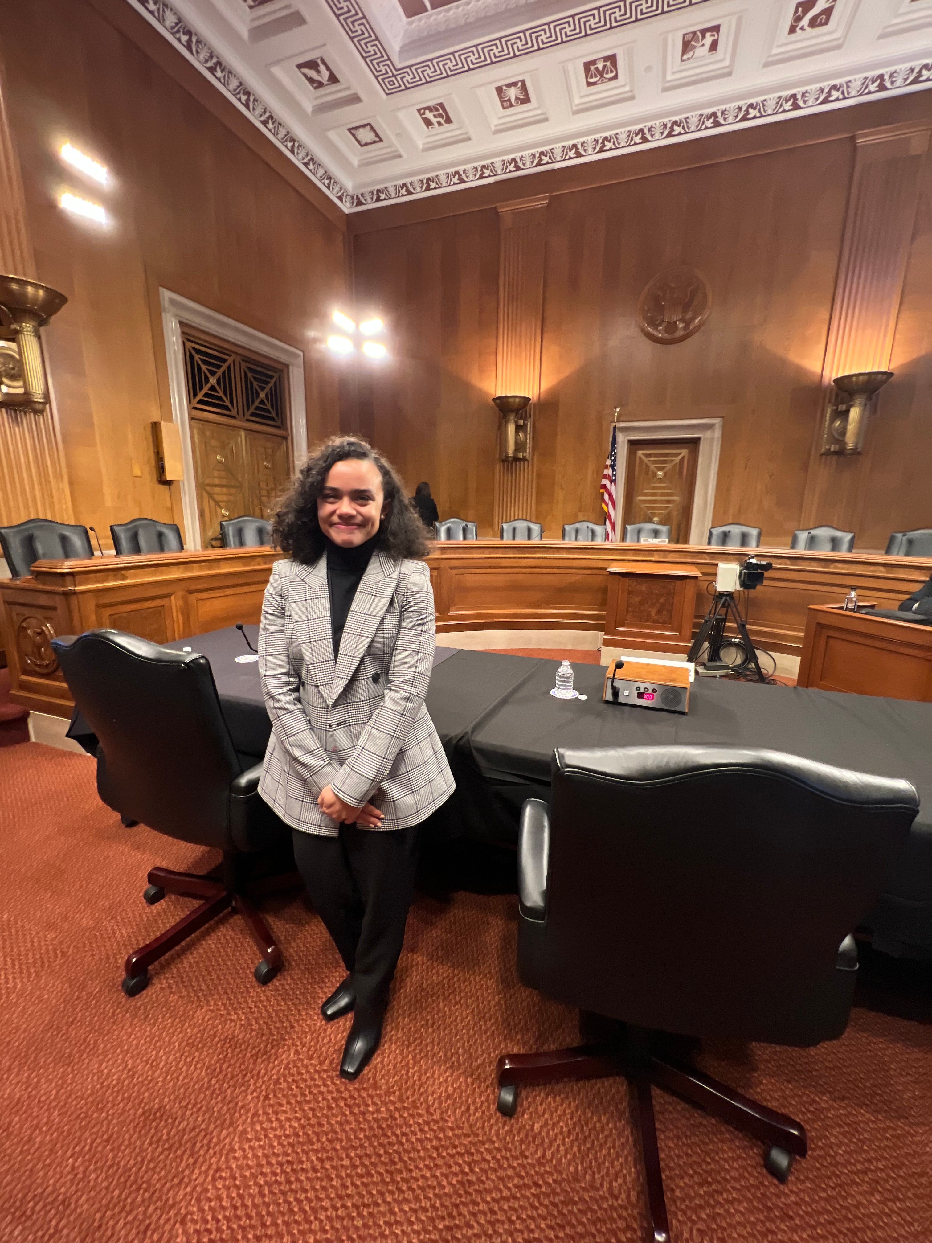 Christina Toppin '21 before a hearing table in an ornate chamber.