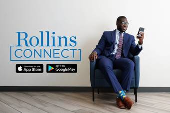 A young man in a blue suit uses the Rollins Connect app on his iPhone.