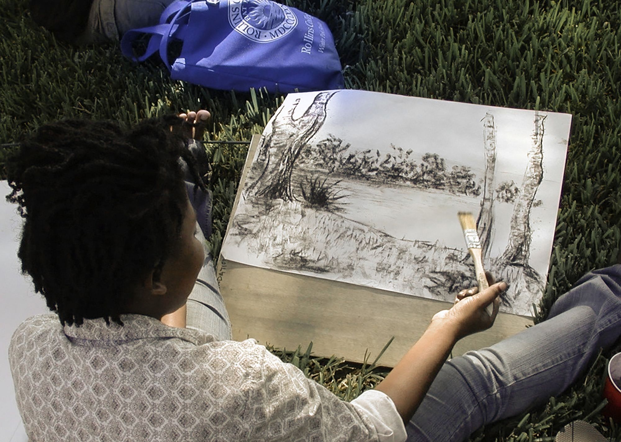 A student paints a landscape of Lake Virginia.