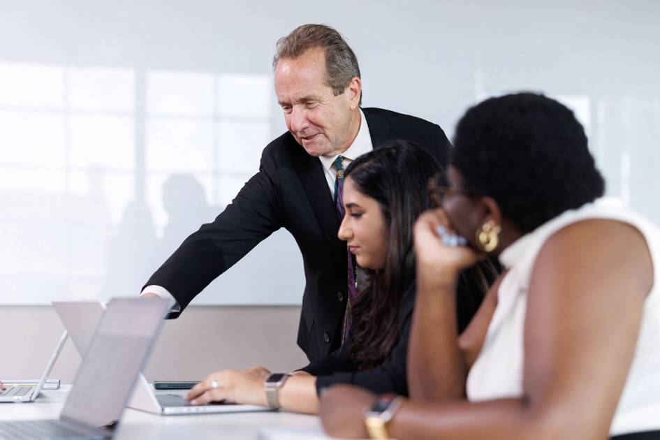A strategic communications professor works one on one with students in class.