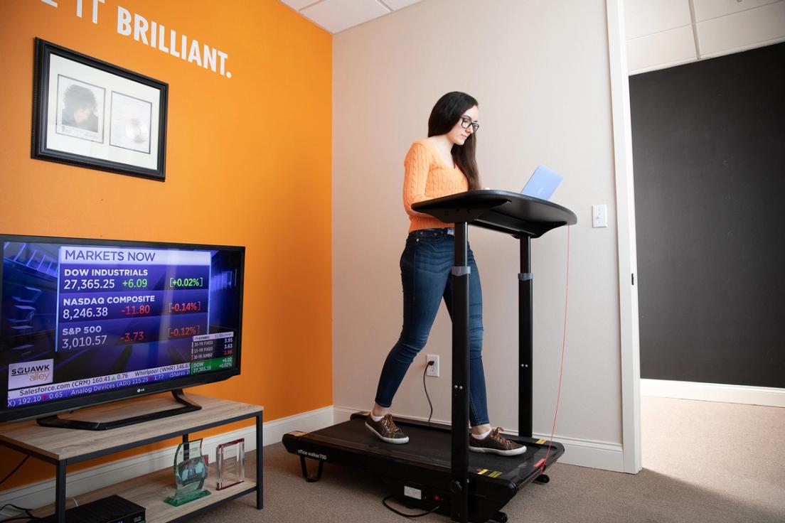 Neny Lairet multitasking, working on her laptop while getting a workout in on the treadmill.