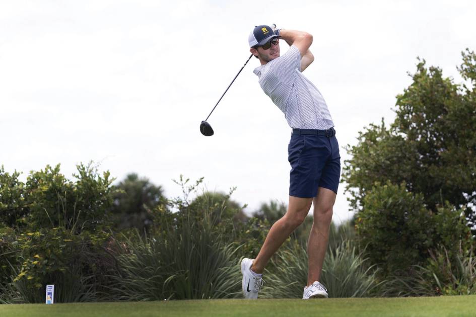 A college golfer tees off.