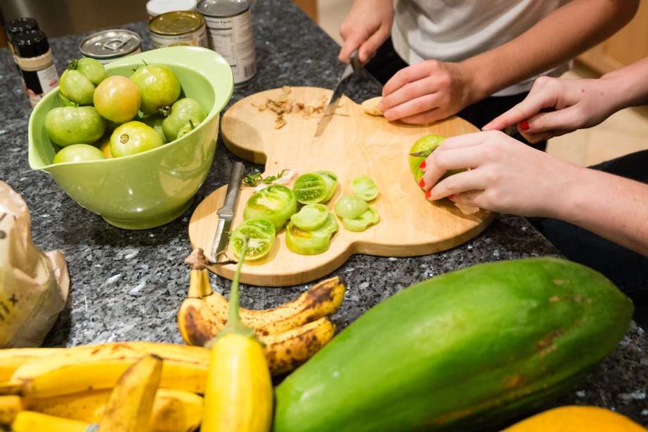 Students slice vegetables for dinner preparation.