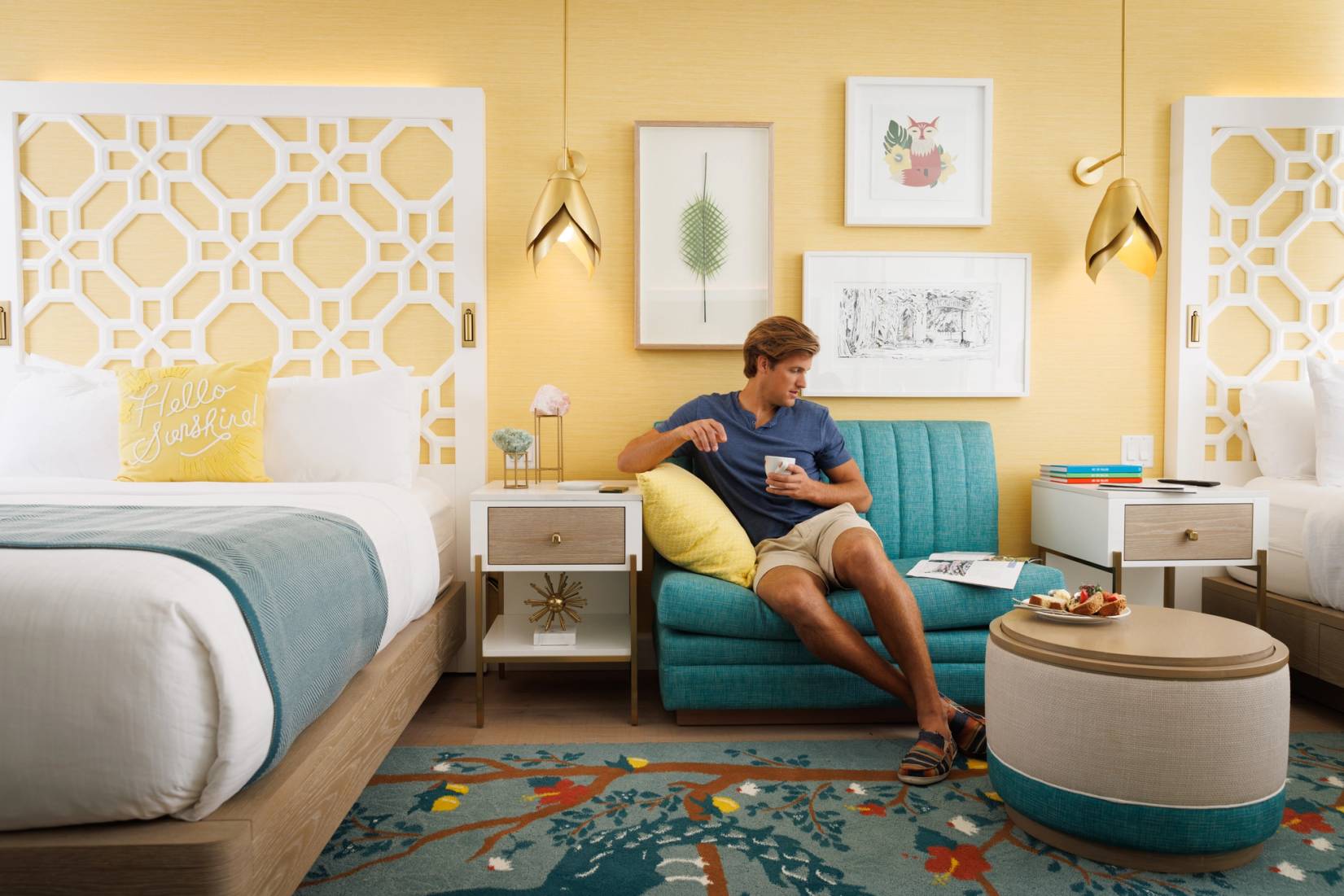 Young man sitting on a sofa in a newly renovated room at the Alfond Inn.