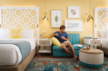 Young man sitting on a sofa in a newly renovated room at the Alfond Inn.