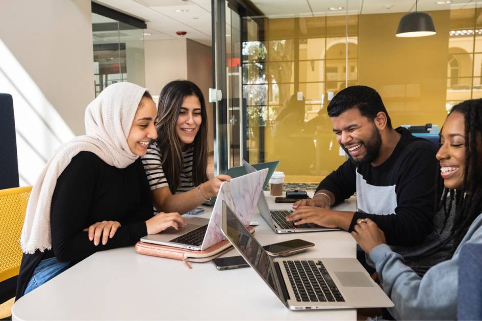 Four students laughing together and planning an organization event.