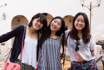 Three Rollins students hug and smile at the camera.